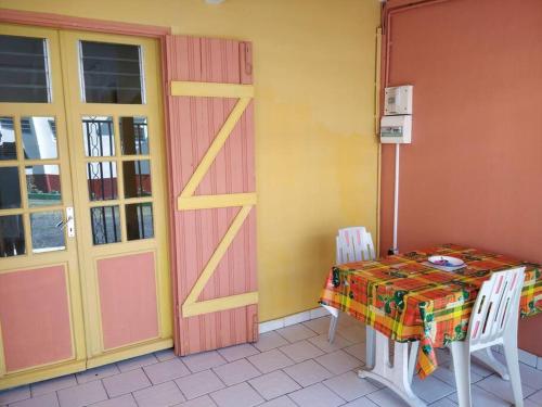 una stanza con tavolo e porta e tavolo e sedie di Bungalow Touloulou (Mi) à 10mn à pieds des plages a Le Gosier