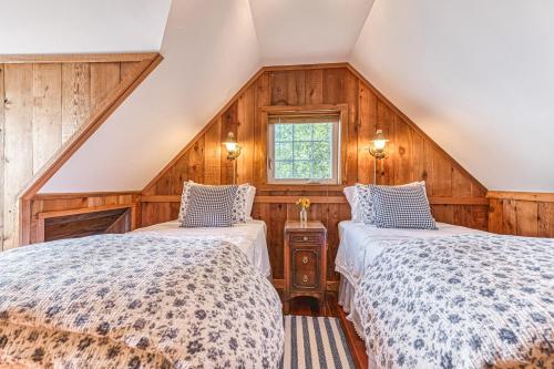 two beds in a room with wooden walls at Ferry Viewer Cottage in Point Roberts