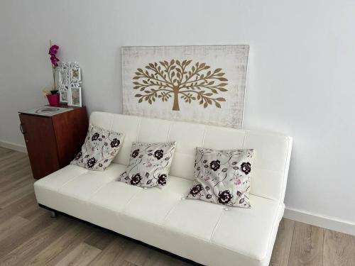 a white couch with three pillows on it in a living room at Light and cozy apartment in Alicante in Alicante