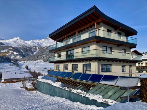 ein großes Gebäude mit Sonnenkollektoren im Schnee in der Unterkunft Apart Pedrolini in Nauders