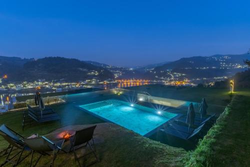 a swimming pool with two chairs and a table at Douro Country House in Cinfães
