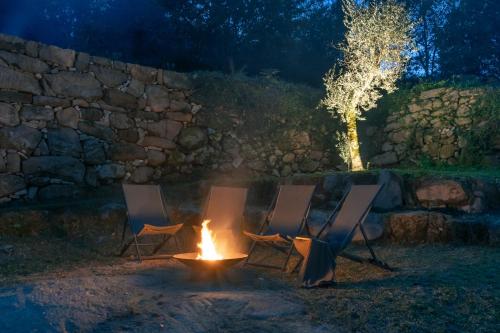 three chairs and a fire pit at night at Douro Country House in Cinfães
