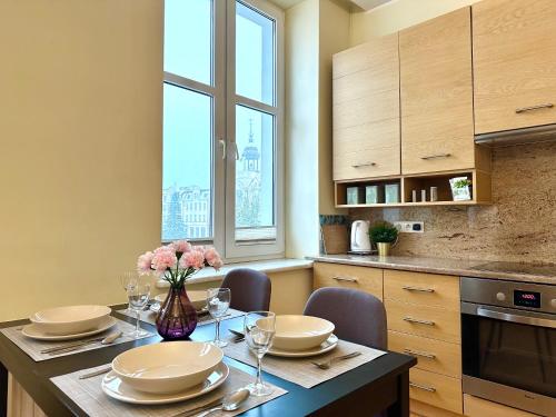 a kitchen with a table with plates and flowers on it at Apartament z widokiem na stary rynek in Wejherowo