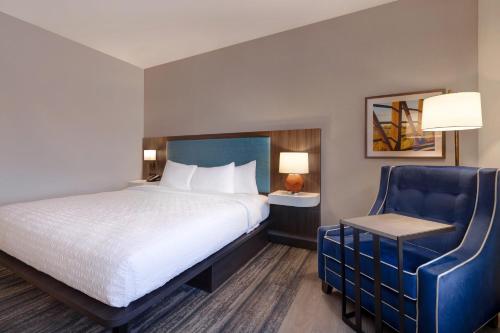 a hotel room with a bed and a blue chair at Hampton Inn Chicago Orland Park in Orland Park