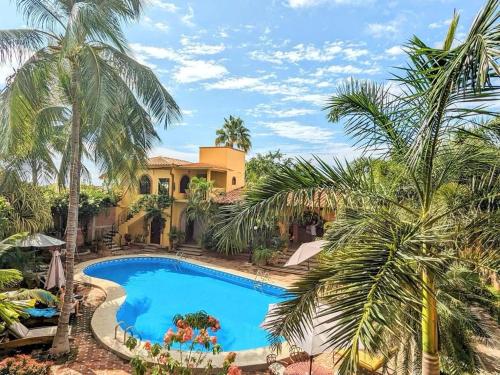 uma piscina em frente a uma casa com palmeiras em Suites La Hacienda em Puerto Escondido