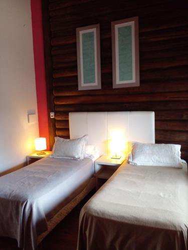 two beds in a room with two lights on them at Los Ancares Resort in Mina Clavero