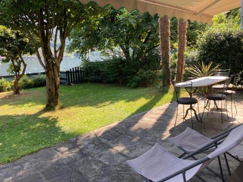 patio con tavolo e sedie sotto ombrellone di Orta cottage sulla riva del lago a Orta San Giulio