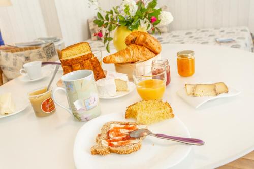 una mesa de desayuno con un plato de comida y pan en Au Jardin des Deux Ponts en Abbeville