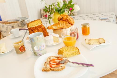 - une table de petit-déjeuner avec une assiette de nourriture et de pain dans l'établissement Au Jardin des Deux Ponts, à Abbeville
