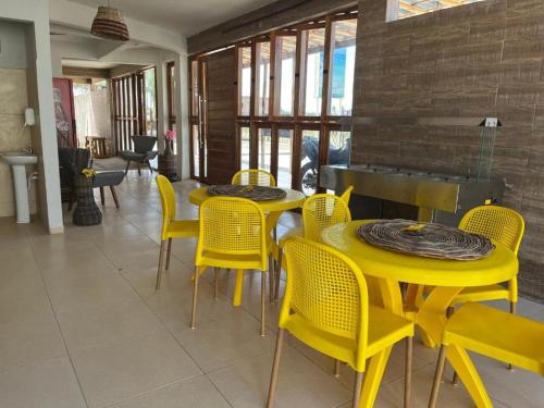 un comedor con mesas amarillas y sillas amarillas en Pousada Belas Praias en São José da Coroa Grande