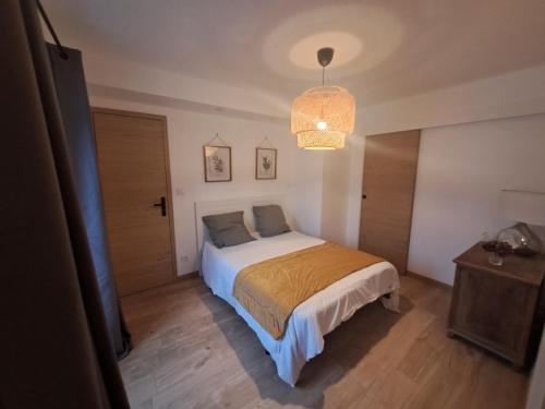 una camera da letto con un letto e un lampadario di La Charmille a Montagnieu