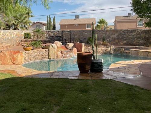 a swimming pool in a yard with a stone wall at Amazing home with custom-built pool in El Paso