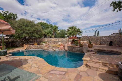 a swimming pool in a yard with a stone wall at Amazing home with custom-built pool in El Paso