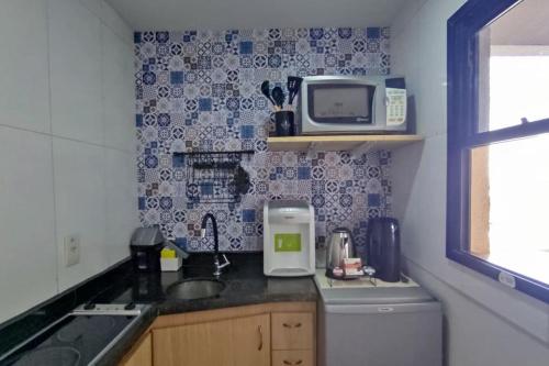 una pequeña cocina con fregadero y microondas en Ap Ipê um quarto no Crystal Place, en Goiânia