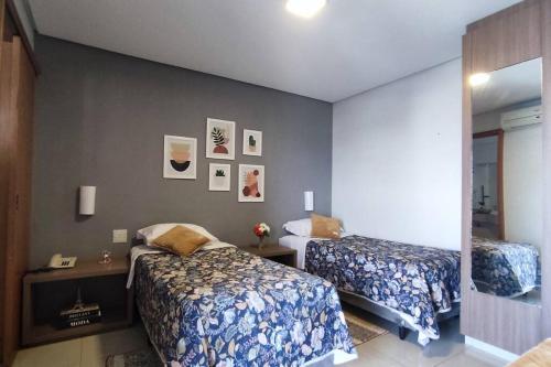 a bedroom with two beds and a wall with pictures at Flat no Crystal Place, a 6 min do Flamboyant in Goiânia