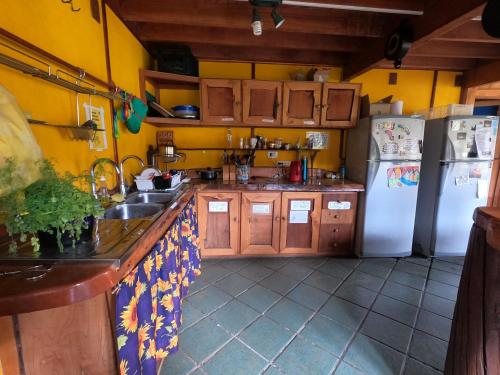 cocina con armarios de madera y nevera blanca en Hostal Las Natalias, en Futaleufú