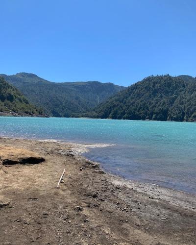 a beach with blue water and mountains in the background at Cabañas & Tinajas Entre Volcanes in Hornopiren