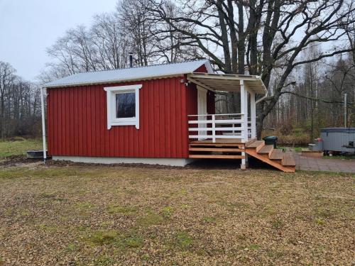 a red shed with a porch and a staircase at Toma pirts MAZĀ in Ikšķile