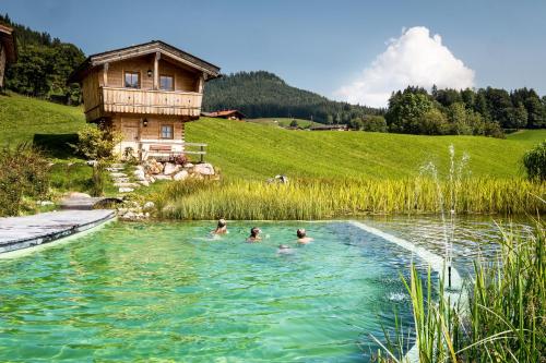 a group of people swimming in a pond at Ettlerlehen Chalets in Ramsau