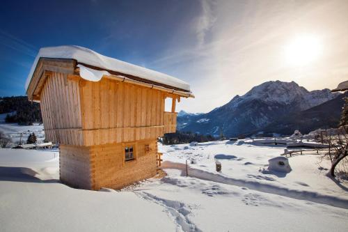 a small wooden building in the snow with a mountain at Ettlerlehen Chalets in Ramsau