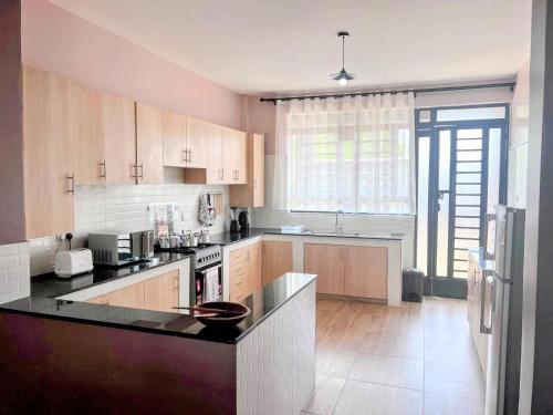 a kitchen with wooden cabinets and a black counter top at Ilala House, Voi - 2 bed, 2 bath in Voi
