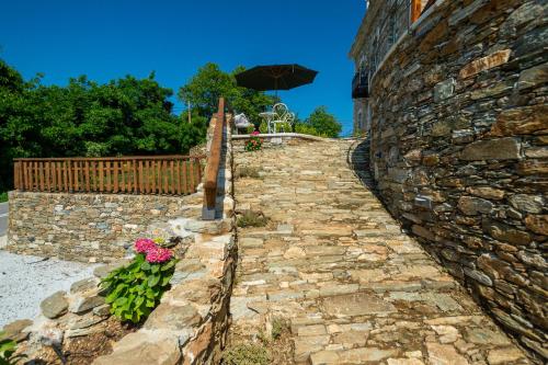 a stone wall with flowers and an umbrella at Nostos Country House in Tsagarada