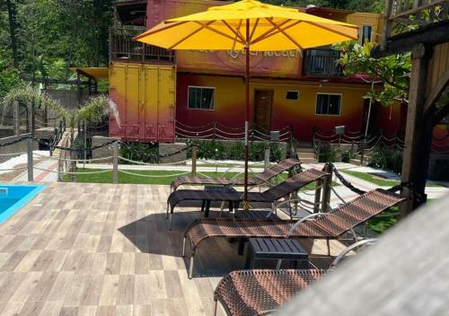 a patio with chairs and an umbrella next to a pool at Pousada São Miguel Beach Beira Mar in Penha