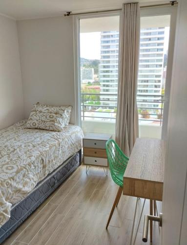 a bedroom with a bed and a desk and a window at Departamento central viña in Viña del Mar