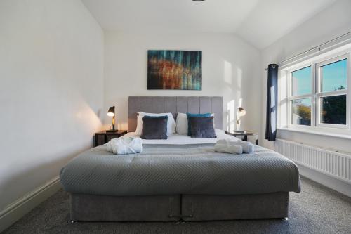 ein Schlafzimmer mit einem großen Bett und zwei Fenstern in der Unterkunft Cross Cottage by YourStays - 2 Bedroom Cottage in Macclesfield in Macclesfield