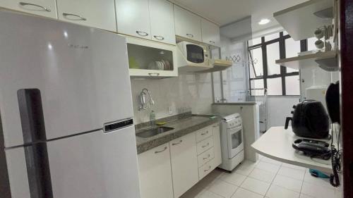 La cuisine blanche est équipée d'un réfrigérateur et d'un évier. dans l'établissement Cabo Frio Elegance Apartament, à Cabo Frio