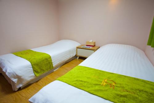 two beds in a small room with green blankets at Jeju R Hotel & Guesthouse in Jeju