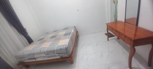 een slaapkamer met een bed en een houten tafel bij Bumi Homestay in Painan