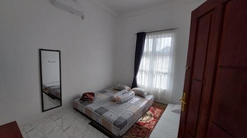 een slaapkamer met een bed, een spiegel en een raam bij Bumi Homestay in Painan