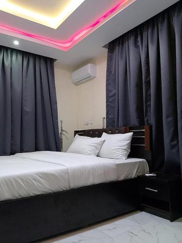 a bedroom with two beds with black curtains at JKA 1-BEDROOM-Apt 24HRS POWER Unlimited WIFI , GARDEN PATIO AREA,FREE DAILY HOUSEKEEPING in Lagos