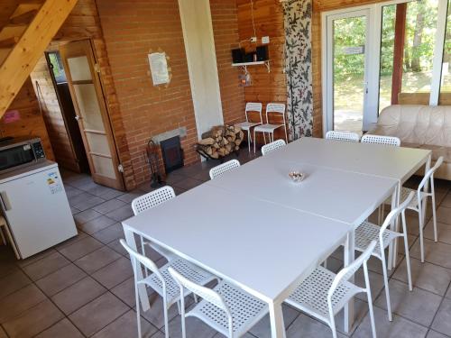 two white tables and chairs in a room with a fireplace at Toma pirts BRĪVDIENU in Ikšķile
