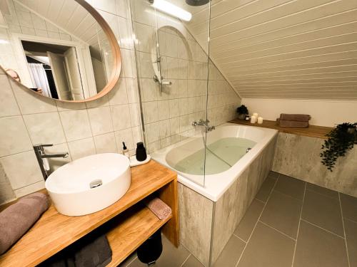 uma casa de banho com um lavatório, uma banheira e um espelho. em Charming Loft Retreat on Tromsø's Historic Main Street: 3-Minute Stroll to City Square em Tromsø