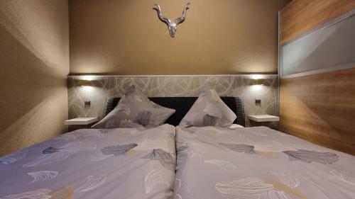 um quarto com uma cama com lençóis brancos e uma cabeceira em Creating Memories em Titisee-Neustadt