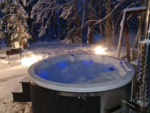 une baignoire jacuzzi dans la neige la nuit dans l'établissement Toma pirts BRĪVDIENU, à Ikšķile