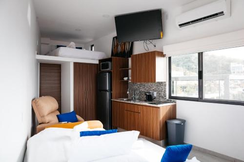 Monyxbnb Hotel في بويرتو فايارتا: غرفة معيشة مع أريكة بيضاء ومطبخ