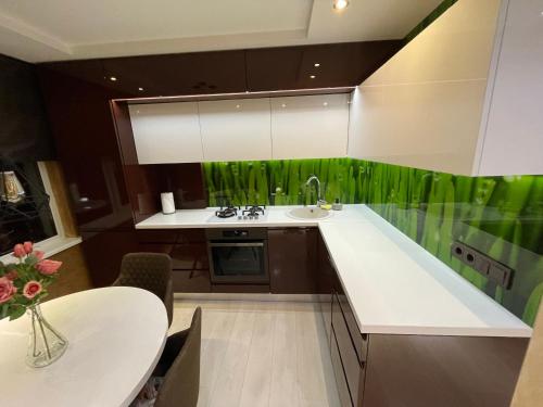 eine Küche mit einer weißen Theke und grünen Tapeten in der Unterkunft Apartment in Šiauliai in Šiauliai