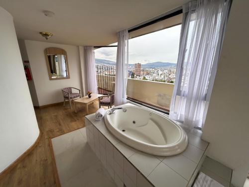 Baño grande con bañera frente a una ventana en Stanford Suites Hotel, en Quito