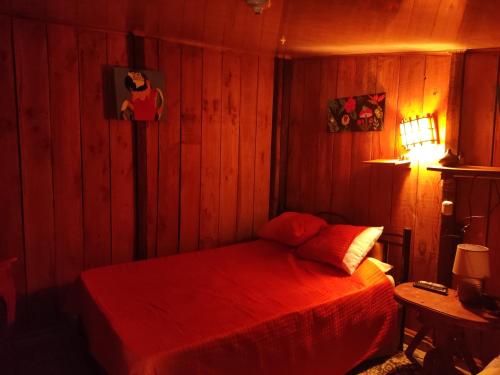 a bedroom with a red bed in a wooden wall at Villa campo's in Venecia