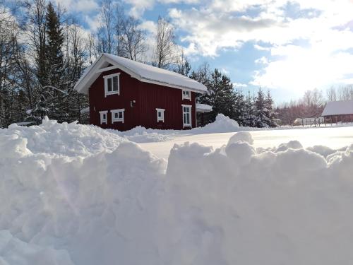 ein Schneehaufen vor einer roten Scheune in der Unterkunft Toma pirts BRĪVDIENU in Ikšķile