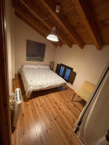 1 dormitorio con 1 cama y suelo de madera en Ático aires de gredos, en Candeleda