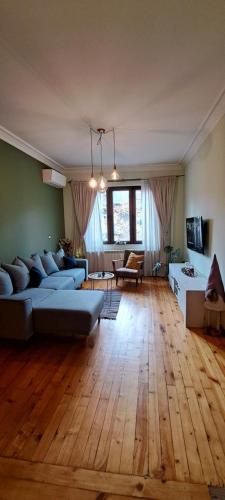 een grote woonkamer met een blauwe bank en houten vloeren bij Top Central 2 Bedroom Apartment next to NDK in Sofia