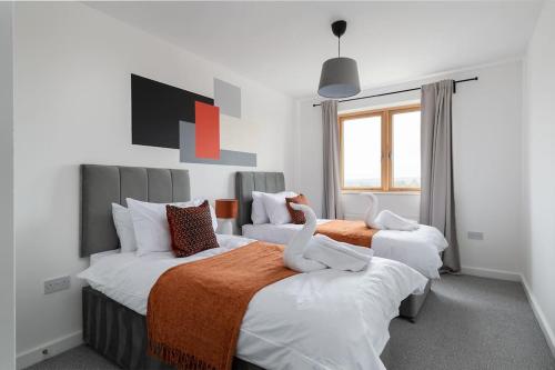 1 dormitorio con 2 camas con sábanas de color naranja y blanco en Luxury 2 bed, Central, Free Parking, Smart TV By Valore Property Services en Milton Keynes