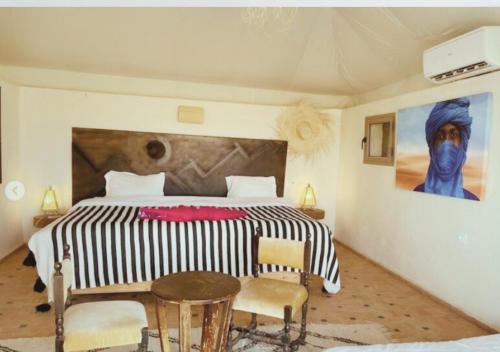 a bedroom with a large bed and a table and chairs at The Original Camp in Aït Daoud