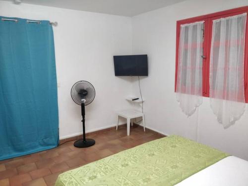 una camera con letto, ventilatore e finestra di Bungalow Paradis Antillais (Do#) à moins de 10mn à pieds des plages a Le Gosier