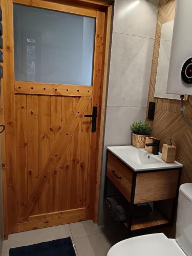a bathroom with a wooden door and a sink at Raj nad Narwią in Zatory