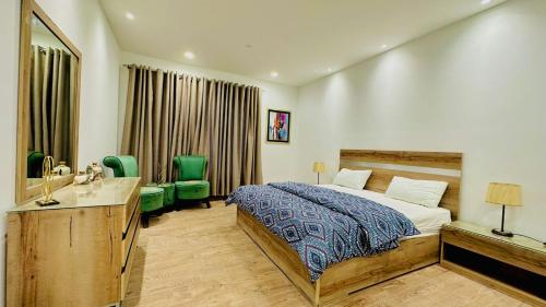 a bedroom with a bed and a sink and green chairs at Premium&Cozy One Bed DHA LHR in Lahore